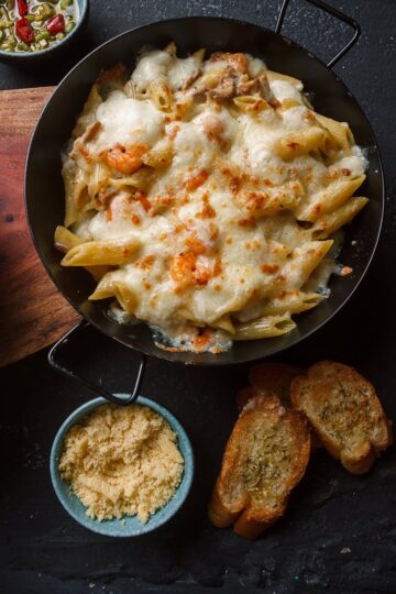 pan with cheesy pasta served on table in kitchen